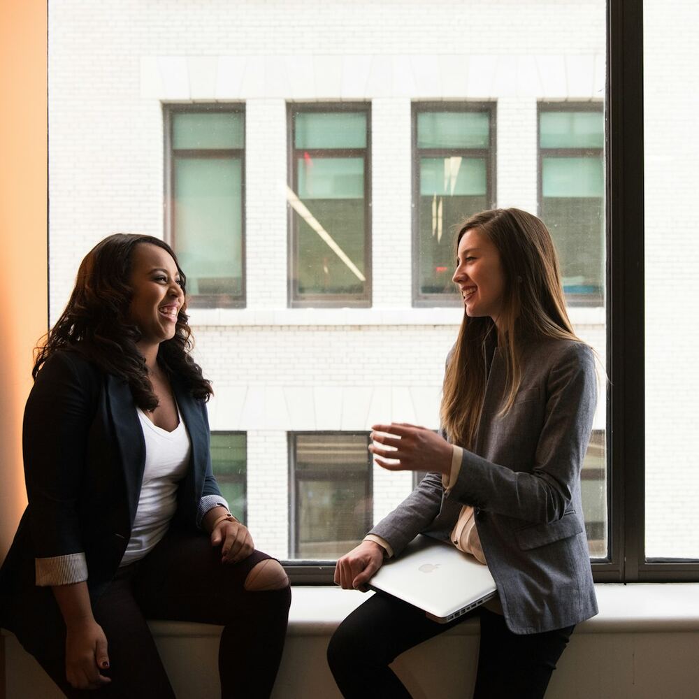 A coaching session — two people talking by a window